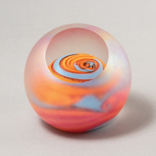 A glass ball with an orange swirl inside of it.
