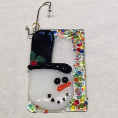 A snowman ornament is displayed on a card.