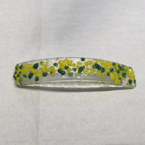 A yellow and green flower bracelet on top of white paper.