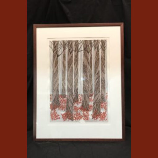A framed picture of trees with red flowers.