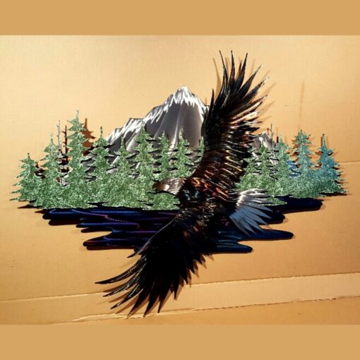 A metal eagle flying over the water with trees in front of it.