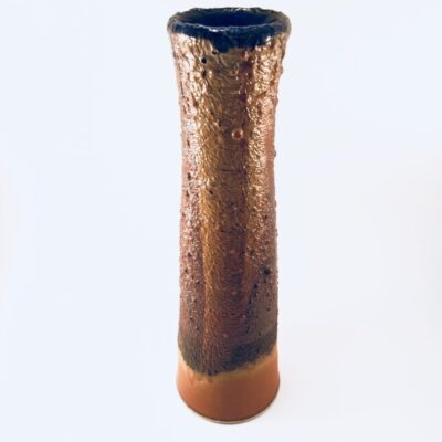 A tall brown vase with black rim and a small blue dot on the bottom.