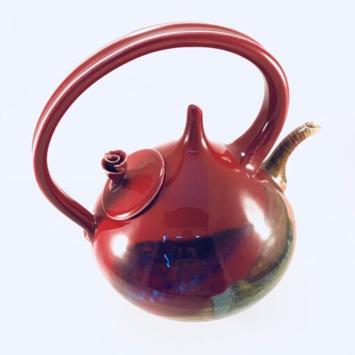 A red teapot with a handle and a round base.