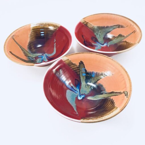 Three bowls with a bird on them sitting in front of each other.