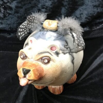 A ceramic dog with feathers on its head.