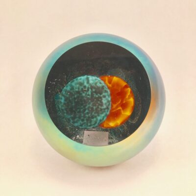 A blue and green glass bowl with an orange sun in it.