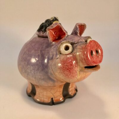 A ceramic pig is sitting on the ground.