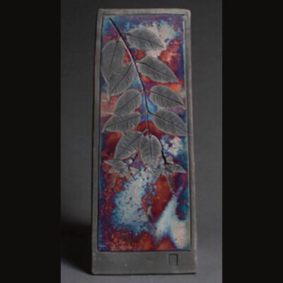 A tall rectangular ceramic tile with leaves and flowers on it.