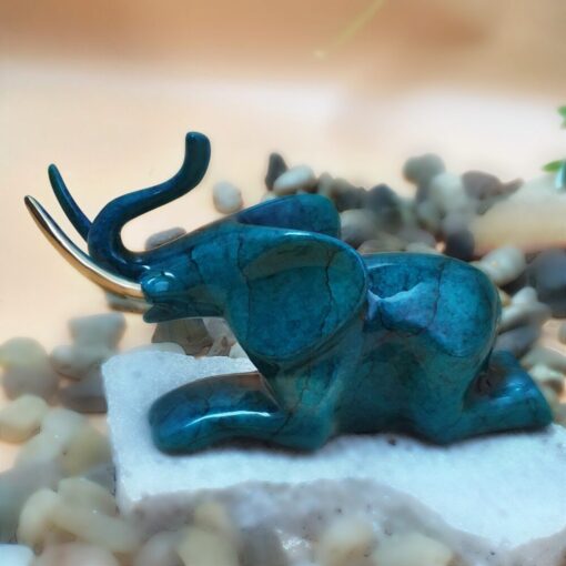 A blue elephant figurine sitting on top of some rocks.