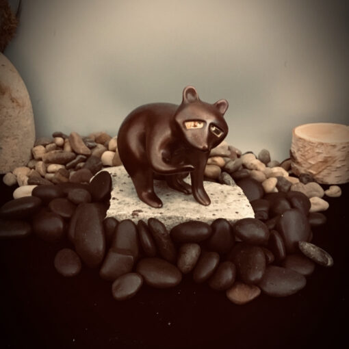 A cat figurine sitting on top of some rocks.