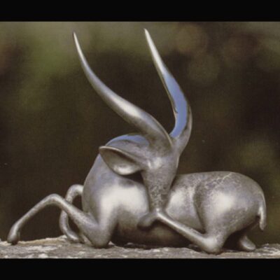 A metal sculpture of two animals laying on top of each other.