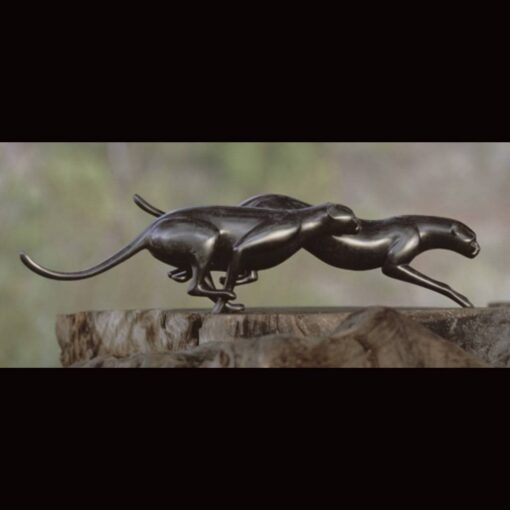 A bronze sculpture of two panthers running on top of rocks.