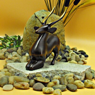 A small antelope statue sitting on top of rocks.