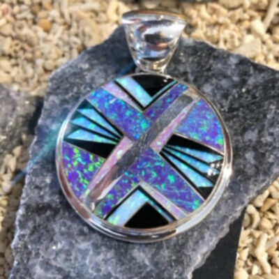 A silver pendant with blue and purple inlay.