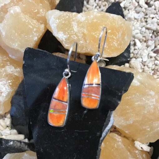 A pair of orange earrings sitting on top of some rocks.