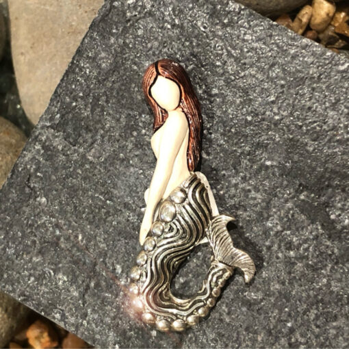 A mermaid is sitting on the rocks.