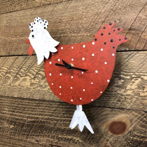 A red and white chicken clock sitting on top of a wooden table.