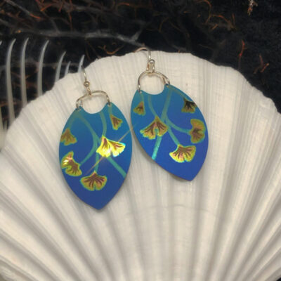 A pair of blue earrings sitting on top of a shell.