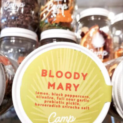 A jar of bloody mary sits in front of other jars.