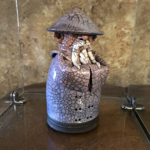 A brown and white jar with a hat on top of it.