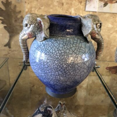 A blue vase with two elephants on top of it.