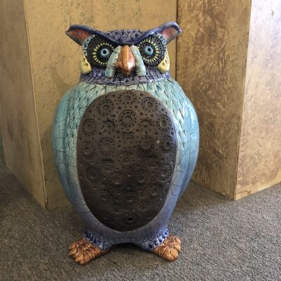 A blue owl statue sitting on the ground.