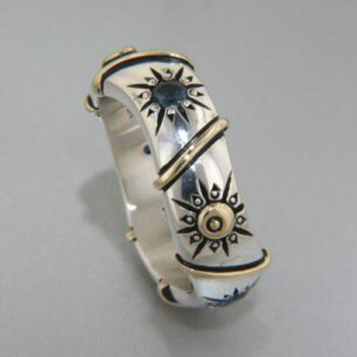 A silver ring with gold sun design on it.