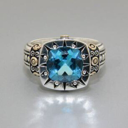 A blue topaz ring is shown on top of a silver and gold ring.