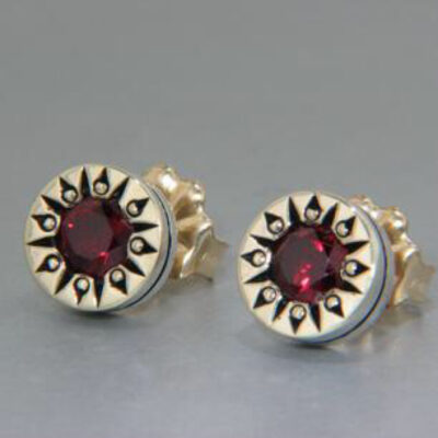 A pair of earrings with red stones on top.