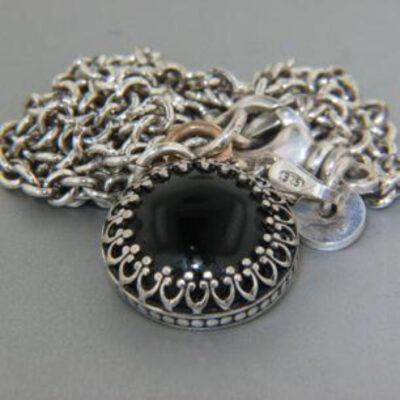 A silver chain with a black stone on it