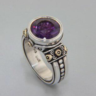 A silver ring with a purple stone on top of it.