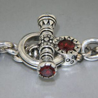 A silver cross with red stones on it.