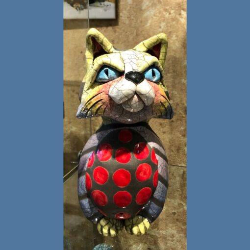 A cat statue with red and black polka dots.