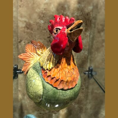 A rooster is hanging on the side of a glass.