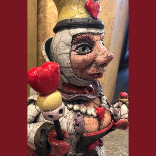 A ceramic clown with a red heart on his head.