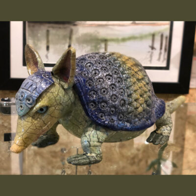 A ceramic armadillo sculpture on display in front of an art piece.