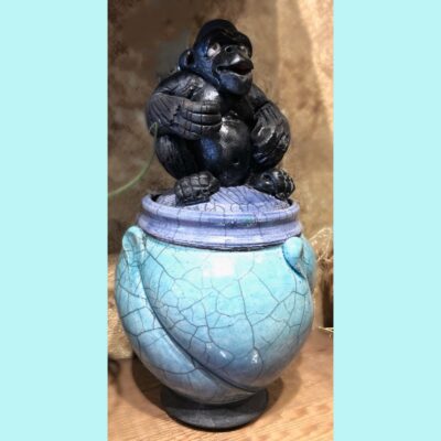 A blue urn with a gorilla on top of it.