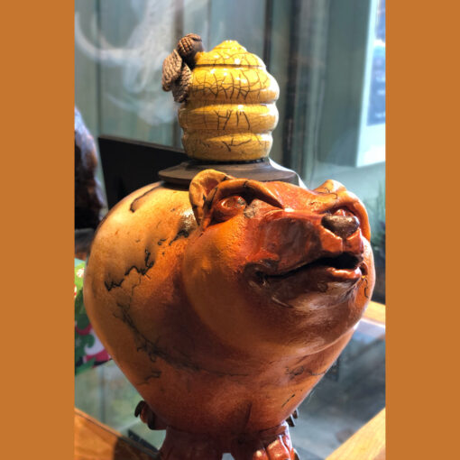 A ceramic pig with a bee on top of it.