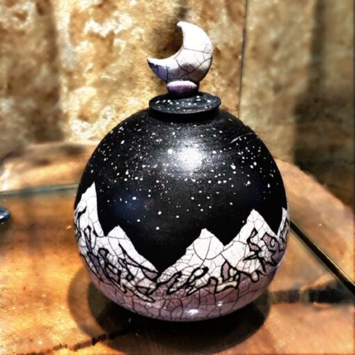 A black and white jar with a moon on top of it.