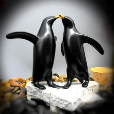 Two penguins are kissing on a rock.