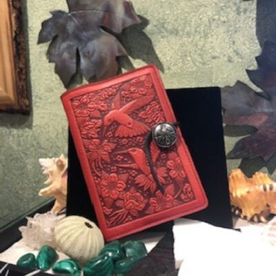 A red book with a black cover on top of some leaves