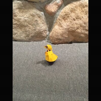 A yellow rubber duck is sitting on the ground.
