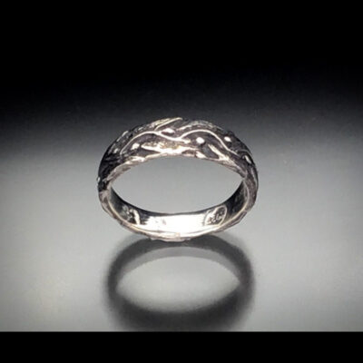 A silver ring with a pattern on it's side.