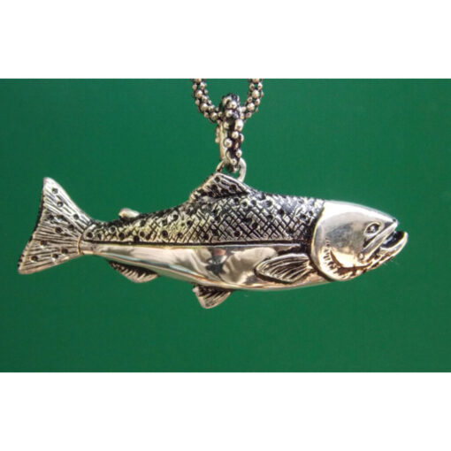 A silver fish necklace hanging on a green background.