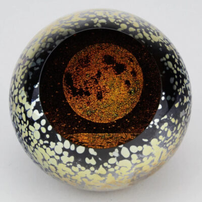 A glass ball with gold and black speckles on it.