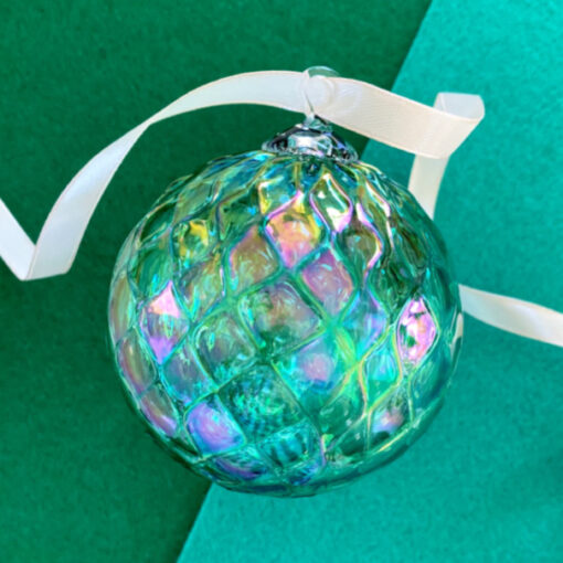 A green ornament with white ribbon on top of it.
